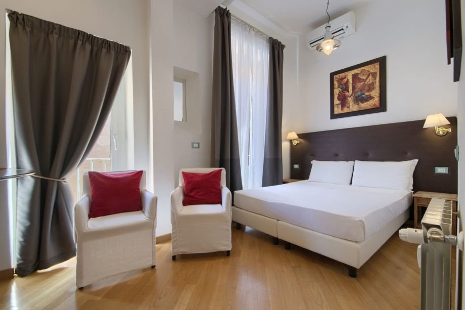 Modern double bed with dark headboard and art paintings in the yellow studio apartment at BB Gli Artisti.