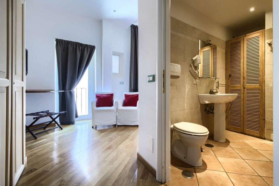 Interior perspective of the studio apartment showing the living area and access to the private bathroom.